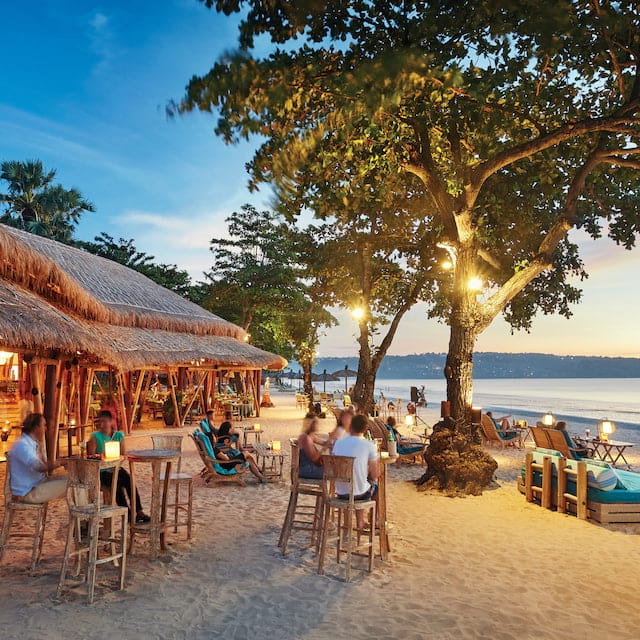 open-air thatched beach hut bar on a white sandy balinese beach