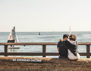 Un couple s'enlace, assis sur un mur surplombant le Pacifique