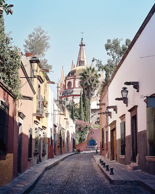 Pastel-coloured homes lining a narrow cobbled road leading to a church