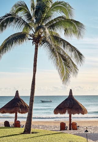 Lettini sotto ombrelloni di paglia su una spiaggia soleggiata