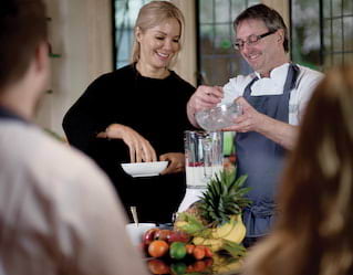 Cookery school instructor and student adding ingredients to a blender