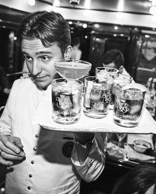 Close-up of a bar steward carrying a tray of drinks